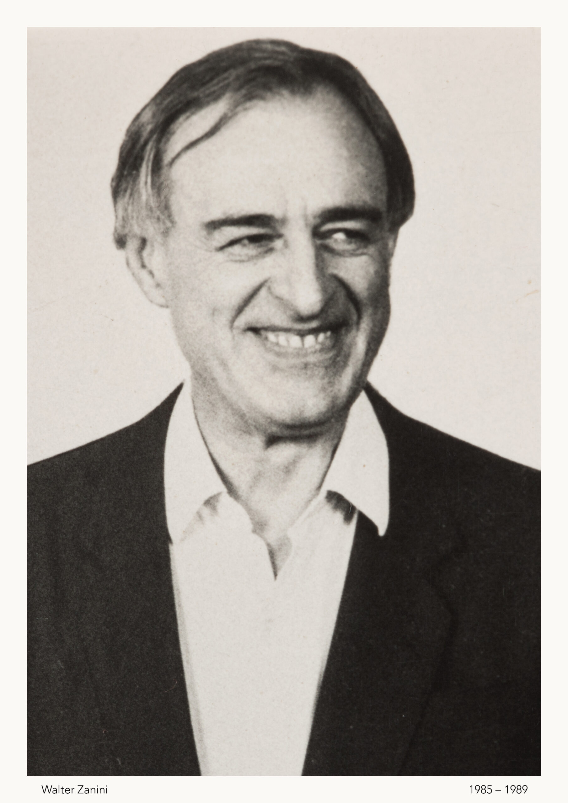 Homem branco, de meia idade, sorridente. Cabelos ralos e despenteados.